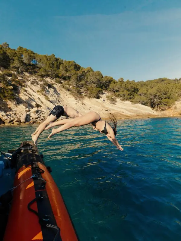 calanques-var-bateau-clients-plongeon-baignade-sea-adventure Clients sautant à l'eau pour une baignade lors de l'excursion bateau dans les calanques du Var avec Sea Adventure